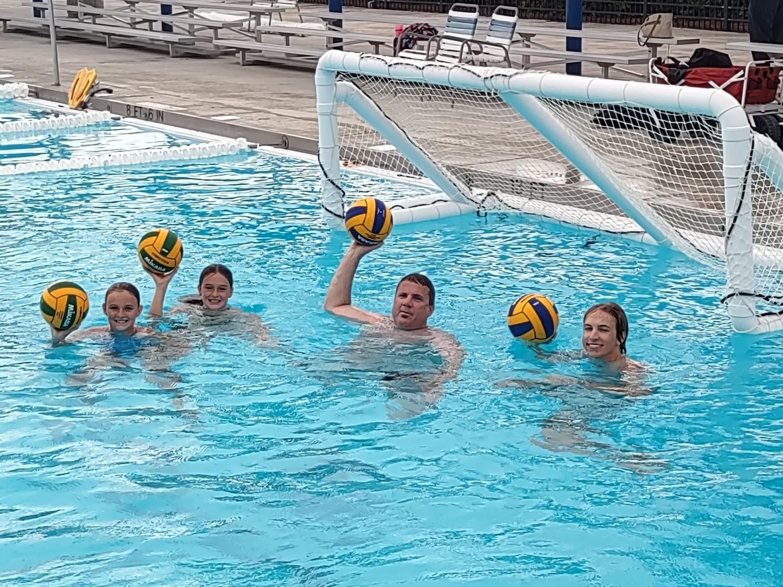 Family water polo moment poolside with balls raised